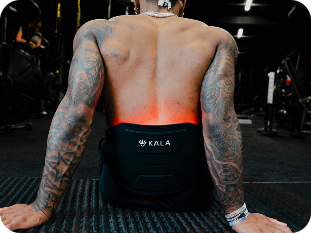 kala red light a tattooed man viewed from behind in a gym, wearing a black KALA waist trainer belt with a glowing red heat light around his lower back.