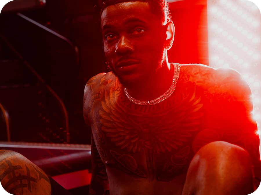 kala red light a close-up lifestyle shot of a tattooed man wearing a silver chain necklace, illuminated by dramatic red lighting.