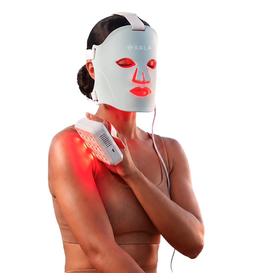 A woman wearing a white KALA red light therapy face mask and holding a matching handheld device against her shoulder, with red light glowing from the devices, on a solid white background.