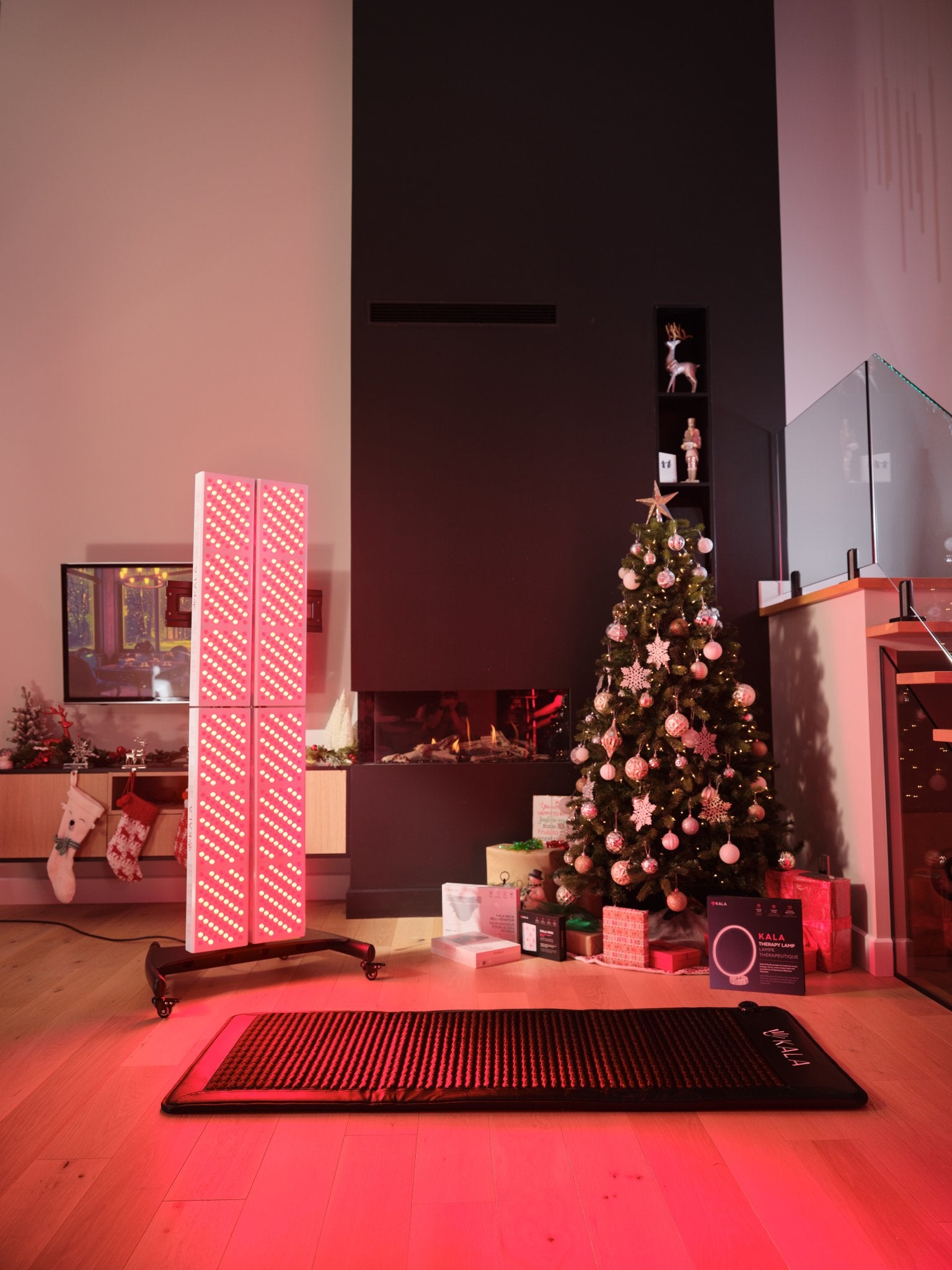 Living room with a Christmas tree, presents, and Kala Red Light Quad Panel delivers commercial-grade red and near-infrared therapy for complete body coverage.