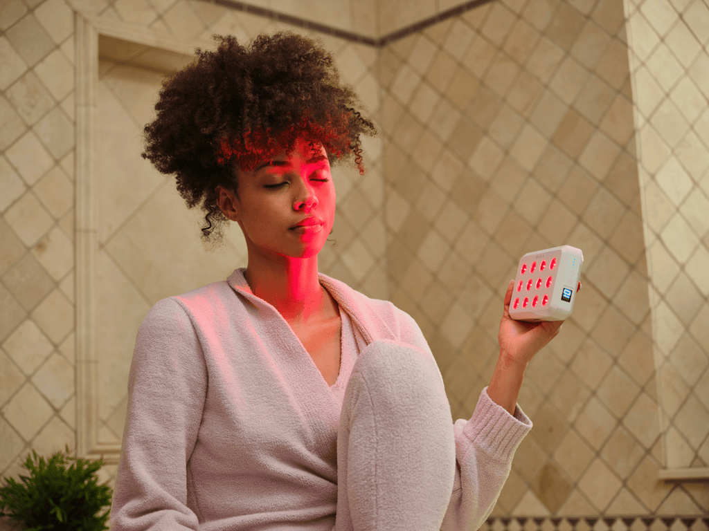 Woman holding a small device with a Kala Red Light Mini 2.0 delivers medical-grade red and near-infrared therapy in a compact, travel-ready design.