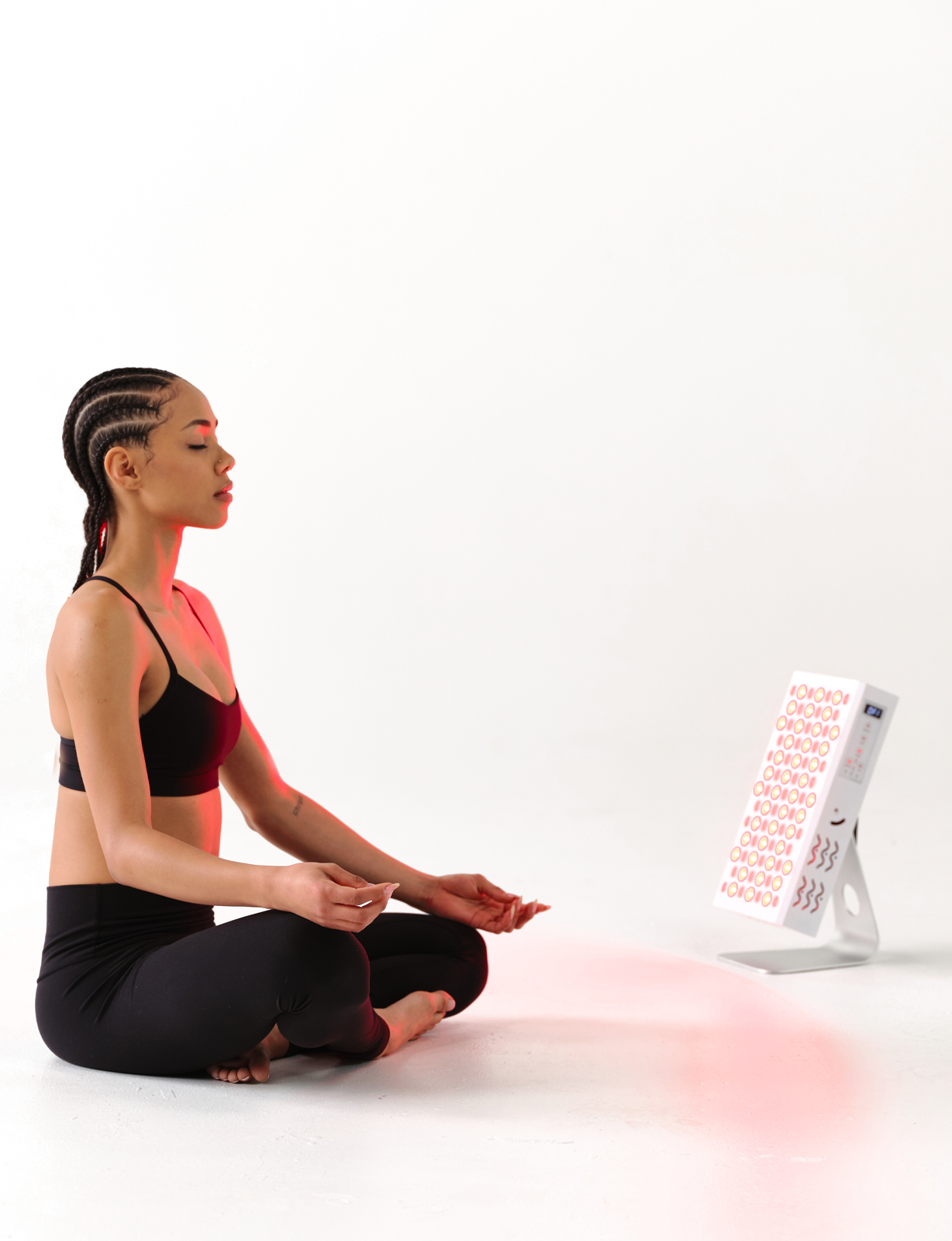 Woman practicing yoga with a red light therapy device panel delivers professional-grade red and near-infrared therapy for half-body coverage.