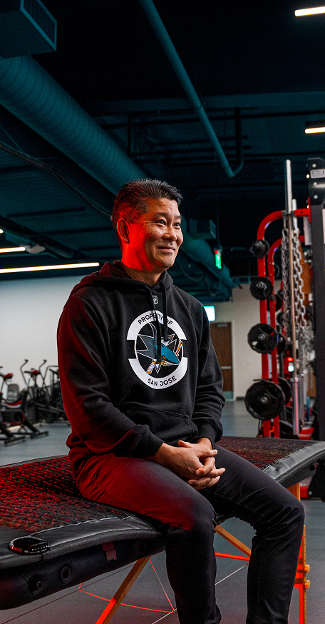 A man sitting on a full-body Kala red light therapy mat inside a high-performance training gym.