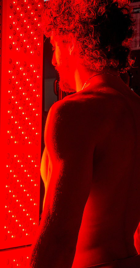 Man standing in front of a full-body Kala red light therapy panel.