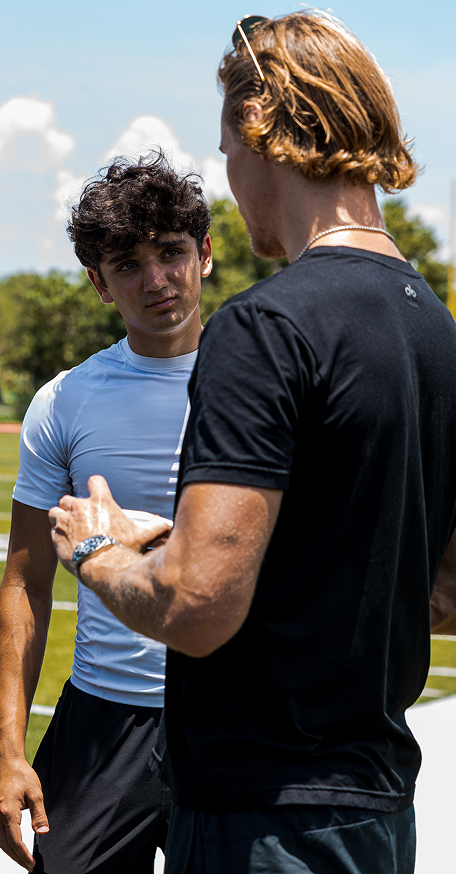 Athletes discussing training performance and Kala red light therapy recovery on a football field.