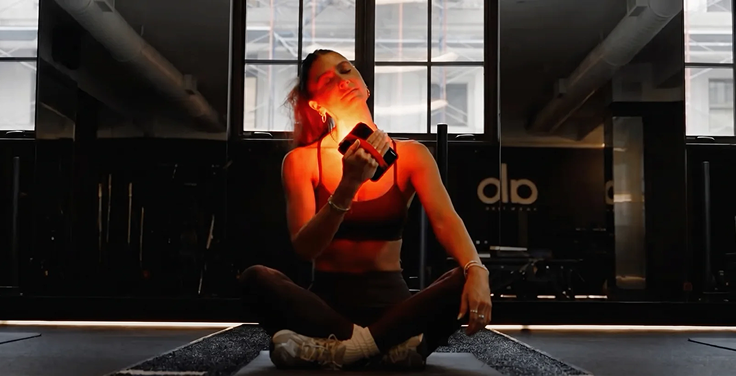 Person using a red light therapy device in a modern indoor setting with 'alp' branding.