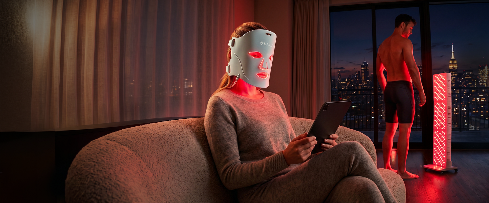 Kala Red Light Therapy devices being used by a woman wearing an illuminated face mask on a sofa and a man standing in front of a tall light panel.