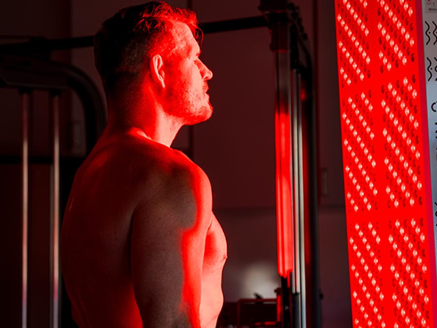 Man standing in front of a kala red light therapy machine