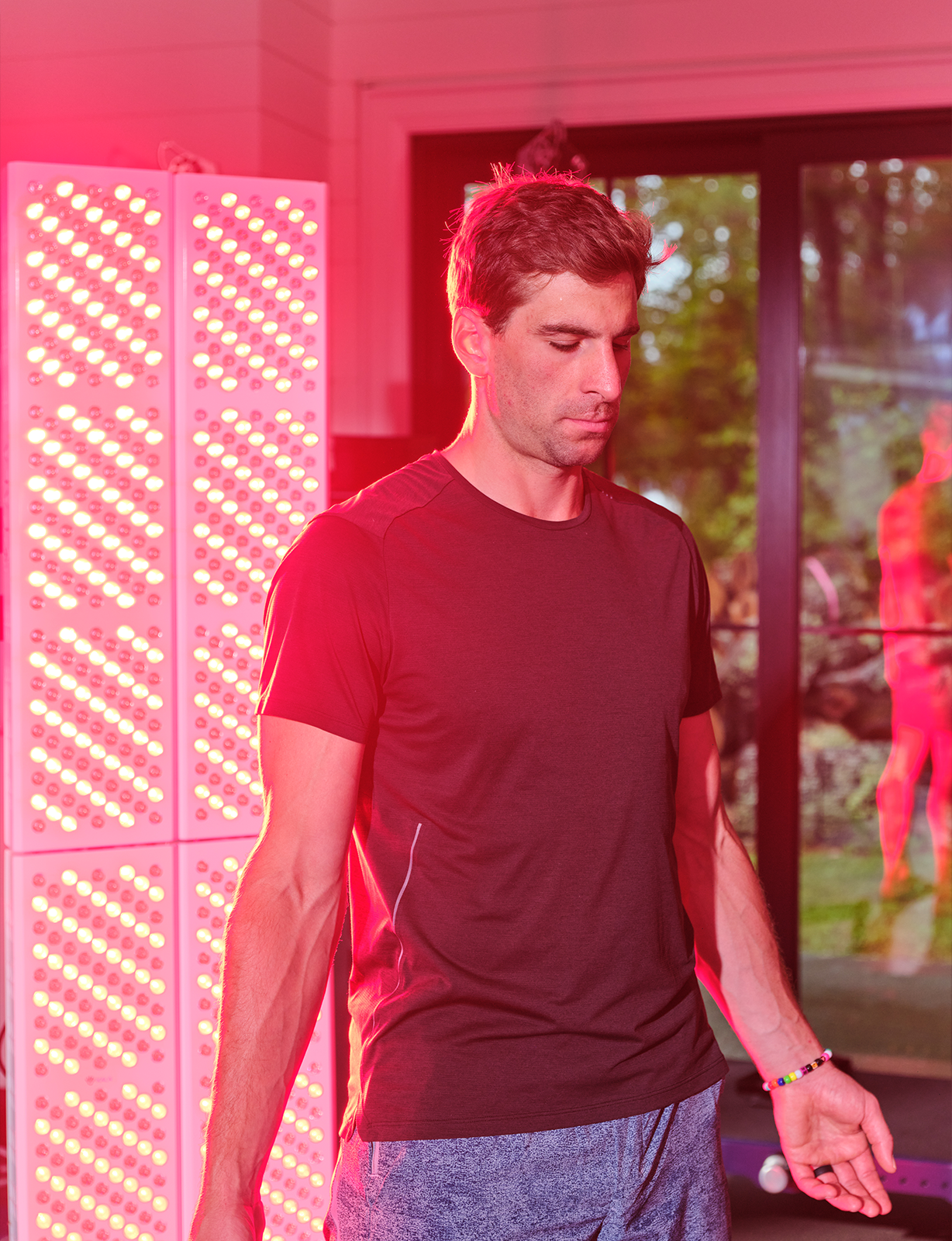 Man wearing a room with kala red lighting and a large screen in the background.
