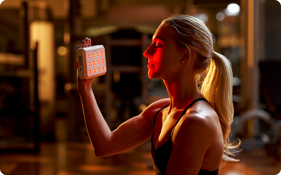 Kala Red Light Woman holding a red light device against her face in a blurred indoor setting