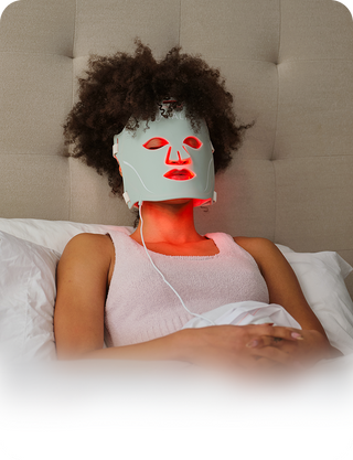 Woman relaxing in bed with a KALA Red Light Therapy face mask for anti-aging, wrinkle reduction, and skin rejuvenation.