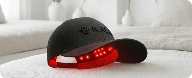KALA red light therapy belt and portable controller resting on a white bed in a bright, modern bedroom.