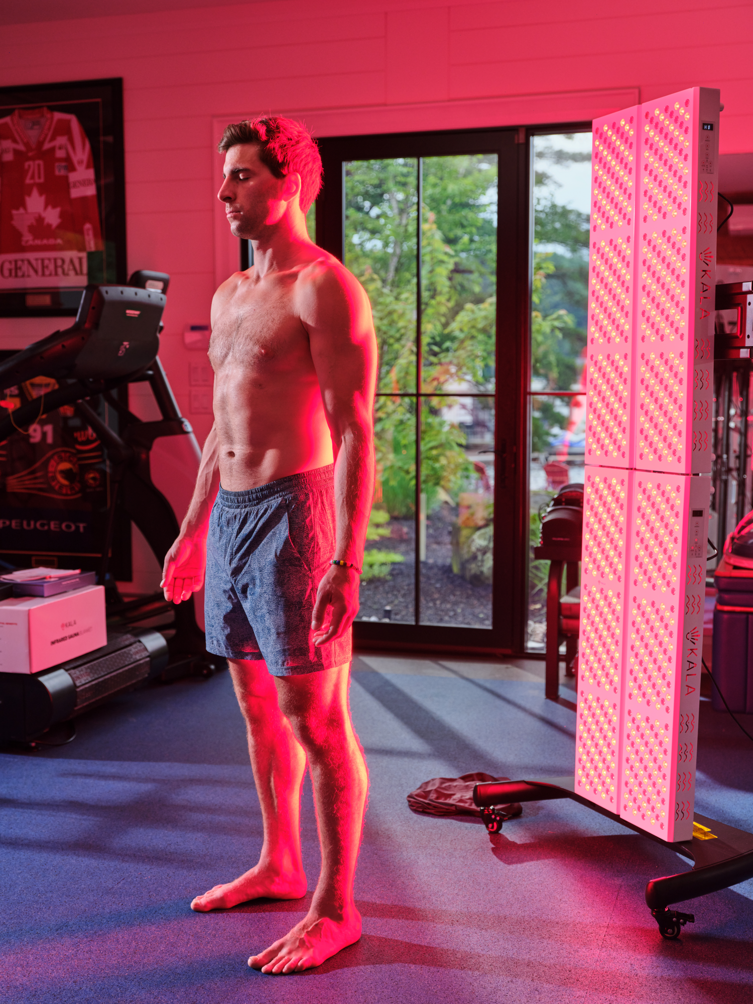 Person using a red light therapy device in a room with a fireplace.